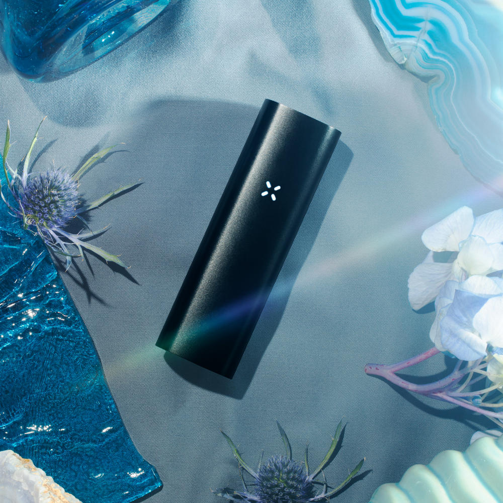 PAX 3 dual-use vape in stylized blue setup featuring flowers and geode slices.